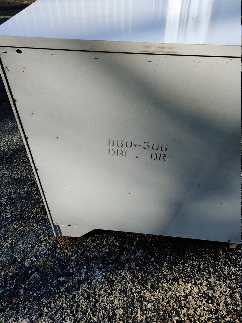 May include: A white metal cabinet with a gray back panel. The back panel has the text "860-506 DBL - DR" printed on it.