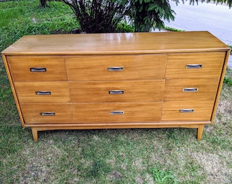 May include: A light wood dresser with six drawers and a cabinet door. The dresser has a simple design with metal drawer pulls.