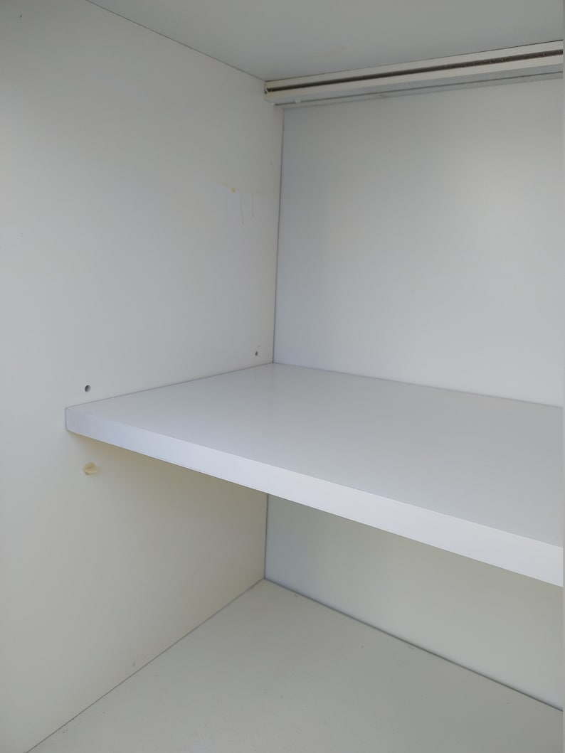 May include: A white shelf unit with a single shelf. The shelf is empty and the unit is made of white wood.