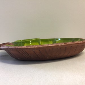 Puede incluir: Un plato de servir de cer&aacute;mica marr&oacute;n con un glaseado verde. El plato tiene una textura tallada de madera y un peque&ntilde;o taz&oacute;n redondo para salsas.