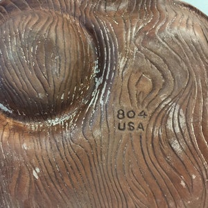 Puede incluir: Un plato de cer&aacute;mica marr&oacute;n con un patr&oacute;n de veta de madera. La parte inferior del plato tiene el texto "804 USA" impreso.