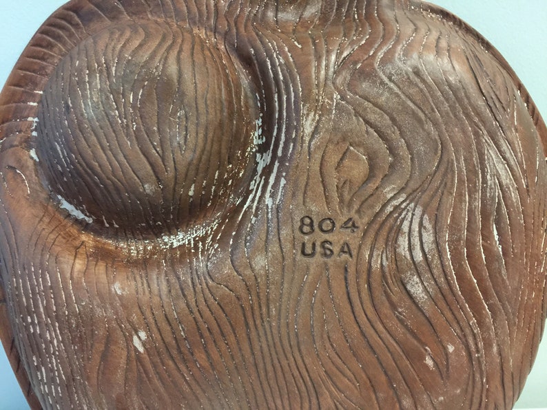 Puede incluir: Un plato de cer&aacute;mica marr&oacute;n con un patr&oacute;n de veta de madera. La parte inferior del plato tiene el texto "804 USA" impreso.