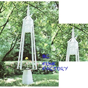 May include: Two white macrame hanging planters with a white tassel fringe. The planters are hanging from tree branches in a green outdoor setting. The text "BC FUNK FACTORY" is visible in the image.