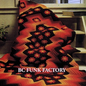 Könnte beinhalten: Handgefertigte Häkeldecke mit einem auffälligen geometrischen Muster in Rot-, Orange- und Schwarztönen. Die Decke hat ein Zickzack-Design mit floralen Akzenten und dem Text "BC FUNK FACTORY".