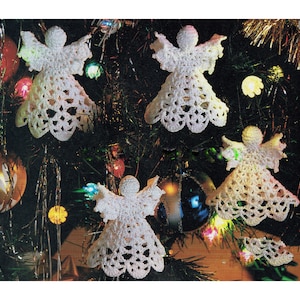 May include: Four white crocheted angel ornaments hanging on a Christmas tree with green branches and colorful lights.