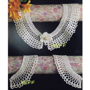 Könnte beinhalten: Weißer Häkelkragen mit einer Blumenverzierung. Der Kragen wird auf einem floral gemusterten Stoffhintergrund gezeigt.