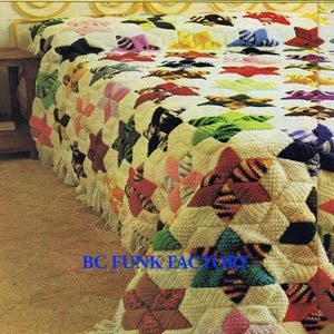 Op de afbeelding: Een gehaakt deken met een sterpatroon in verschillende kleuren, waaronder roze, groen, blauw en geel. Het deken is gemaakt van een zacht, getextureerd garen en heeft een franje rand.