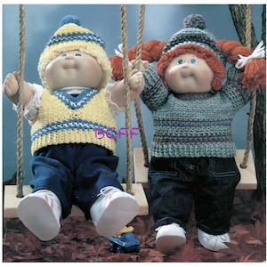 Könnte beinhalten: Zwei Cabbage Patch Kids Puppen auf einer Schaukel. Die Puppe links trägt eine gelbe und blaue gehäkelte Weste, eine gelbe und blaue gestreifte Mütze und eine blaue Jeans. Die Puppe rechts trägt einen grün und braun gestreiften gehäkelten Pullover, eine rot und weiße gestreifte Mütze und eine blaue Jeans.
