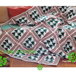 May include: A green, white, and red crocheted throw blanket with a pine tree pattern. The blanket is folded on a couch and the text "Pine Tree Afghan" is visible in the bottom right corner.