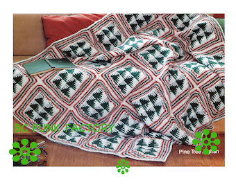 May include: A green, white, and red crocheted throw blanket with a pine tree pattern. The blanket is folded on a couch and the text "Pine Tree Afghan" is visible in the bottom right corner.