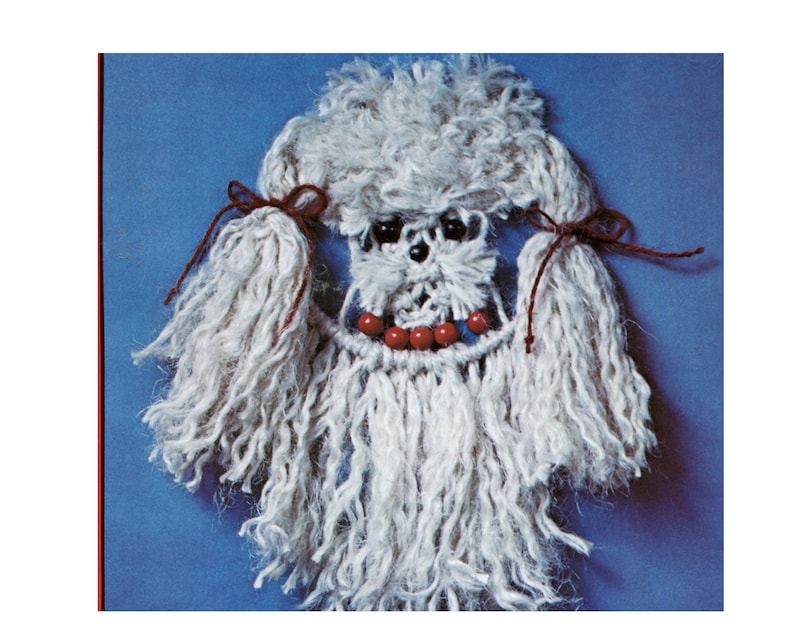 May include: White yarn poodle with red yarn bows and red beads around its neck.