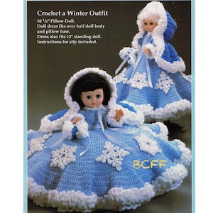 May include: Crochet pattern for a winter outfit for a 10 1/2 inch pillow doll or a 13 inch standing doll. The outfit is blue with white snowflakes and a white hooded cape.
