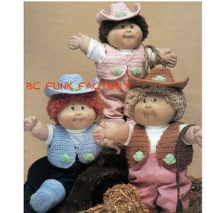 May include: Three Cabbage Patch Kids dolls wearing crocheted cowboy hats and vests. The dolls are wearing pink, blue, and brown pants. The dolls are sitting on a bale of hay.