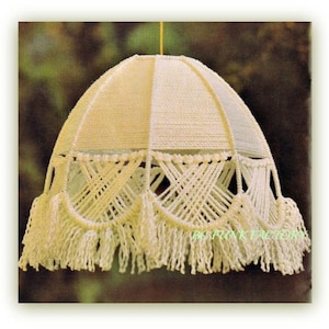 May include: A white macrame lampshade with a fringe border. The lampshade is made with a knotting technique and has a dome shape.