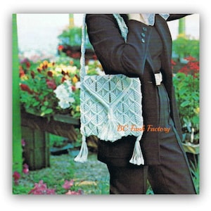 May include: A white macrame bag with a tassel hanging from the bottom. The bag is worn over the shoulder of a person wearing a black outfit. The bag has a geometric pattern.