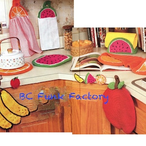 Peut inclure: Accessoires de cuisine en crochet sur le thème des fruits, comprenant un torchon en forme de banane, un dessous de plat en forme de pastèque, un porte-pot en forme d'orange et un torchon en forme de pomme. Le texte "BC Funk Factory" est visible sur l'image.