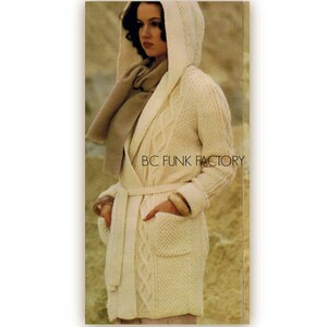 May include: A white knitted hooded cardigan with a cable knit pattern and a brown scarf. The cardigan has a tie belt and pockets.