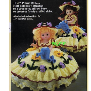 May include: Two crocheted pillow dolls dressed in yellow dresses with floral accents. The dolls are holding blue watering cans. The dolls are 10 1/2 inches tall and the pattern also includes directions for a 13 inch bed doll dress.