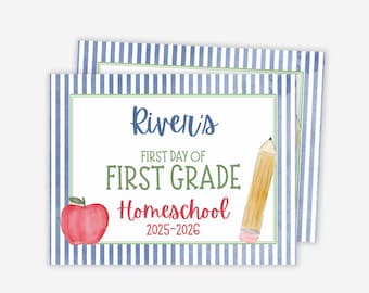 May include: Two rectangular signs with blue and white striped borders. The signs have a white center with text that reads "River's FIRST DAY OF FIRST GRADE Homeschool 2025-2026". An apple and pencil are illustrated.