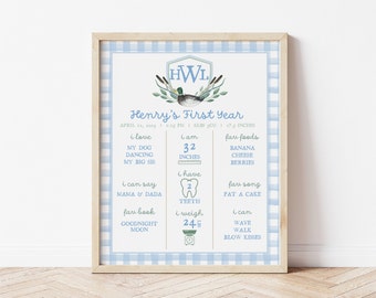 May include: A blue and white gingham background with a light blue frame. The frame contains a printable chart with a duck illustration and the text "Henry's First Year". The chart lists details about the baby's first year, including weight, height, favorite foods, and favorite songs.