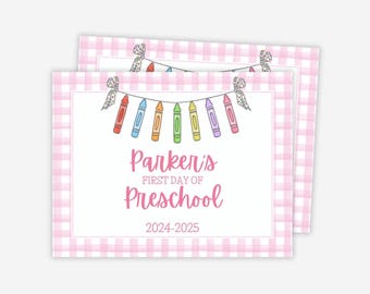 May include: Two rectangular cards with a pink gingham border. The cards have a white center with the text "Parker's First Day of Preschool 2024-2025". A string of colorful crayons hangs above the text.