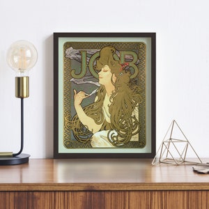 Puede incluir: Un cartel vintage de estilo art nouveau con una mujer de cabello largo y fluido, sosteniendo una pluma estilogr&aacute;fica. El cartel est&aacute; enmarcado en un marco marr&oacute;n oscuro y tiene un fondo verde y dorado con la palabra "JOB" en la esquina superior izquierda.
