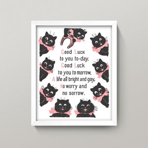 May include: A white framed print with a black and white illustration of eight black cats with pink bows. The cats are arranged in a circle around a poem that reads "Good Luck to you to-day, Good Luck to you to morrow, A life all bright and gay, No worry and no sorrow."