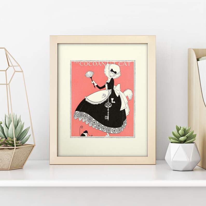 Może przedstawiać: Ilustracja w ramie przedstawiająca kota ubranego w str&oacute;j pokoj&oacute;wki, trzymającego pi&oacute;ropusz. Kot ma na sobie czarną sukienkę z białym fartuchem i białym czepkiem. Tekst "The Coconut Cat" jest nadrukowany nad kotem. Ilustracja jest na r&oacute;żowym tle.