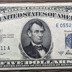 May include: A five dollar bill featuring a portrait of Abraham Lincoln. The bill is dated 1953 and has the serial number E 05523211 A. The Treasury Secretary's signature is Robert Anderson.