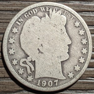 May include: A silver US half dollar coin with the year 1907 and the words "In God We Trust" around the edge.