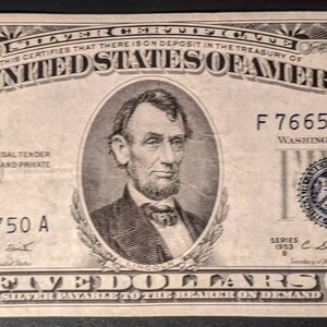 May include: A vintage five dollar bill featuring a portrait of Abraham Lincoln. The bill is in black and white with blue accents. The bill has the serial number F 76655750 A.