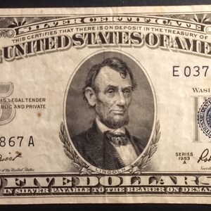 May include: A five dollar bill with a portrait of Abraham Lincoln. The bill is dated 1953 and has the serial number E 03742867 A. The text "THIS CERTIFIES THAT THERE IS ON DEPOSIT IN THE TREASURY OF THE UNITED STATES OF AMERICA" is printed on the bill.
