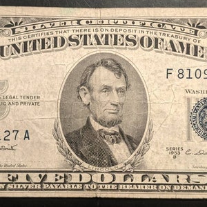 May include: A vintage five dollar silver certificate featuring a portrait of Abraham Lincoln. The certificate is dated 1953 and has the serial number F 81098127 A.
