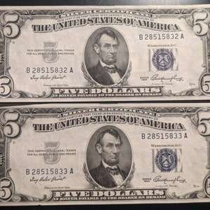 May include: Two $5 US bills from 1953 with the serial numbers B 28515832 A and B 28515833 A. The bills feature a portrait of Abraham Lincoln and the text "THE UNITED STATES OF AMERICA".