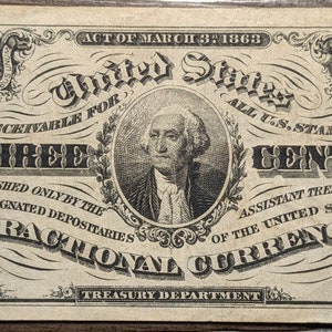 Puede incluir: Una imagen en blanco y negro de un billete de moneda fraccional de tres centavos de los Estados Unidos. El billete presenta un retrato de George Washington y el texto "Act of March 3, 1863", "United States", "Receivable for all U.S. Stamps", "Three Cents", "Furnished only by the & designated depositaries", "Fractional Currency", y "Treasury Department".