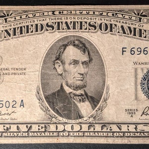 May include: A five dollar bill from the United States of America, featuring a portrait of Abraham Lincoln. The bill is dated 1953 and has the serial number F 69655502 A.