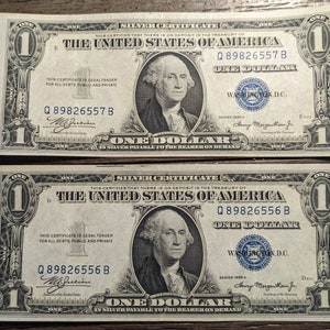 May include: Two vintage US one dollar bills featuring a portrait of George Washington. The bills are in good condition and have the serial numbers Q 89826557 B and Q 89826556 B.