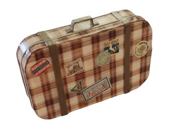 May include: A rectangular suitcase featuring a brown and cream plaid pattern with two vertical brown straps and a top handle. The exterior is decorated with various vintage-style travel stickers, including labels for Halifax, Bombay, and Berlin hotels.