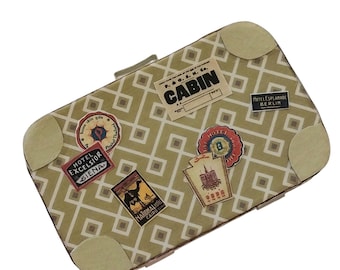 May include: A rectangular clutch bag with a light olive green and white geometric lattice pattern. The bag features four beige corner reinforcements and several vintage-style travel stickers, including labels for Cabin, Hotel Excelsior Siena, and National Hotel Cairo.