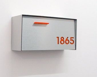 May include: A silver mailbox with a black trim and an orange number "1865" on the front.