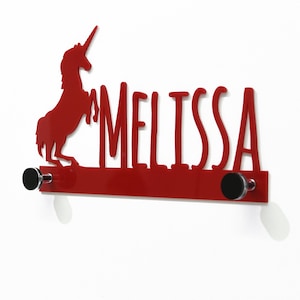 Könnte beinhalten: Roter Metall-Kleiderhaken mit zwei Haken. Der Kleiderhaken zeigt eine Silhouette eines Einhorns und den Namen "MELISSA" in einer stilisierten Schrift.