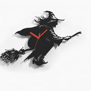 Könnte beinhalten: Schwarze Silhouette einer Hexe, die auf einem Besen fliegt, mit roten Uhrzeigern. Die Uhr ist so gestaltet, dass sie wie eine Hexe aussieht, die auf einem Besen fliegt. Der Text "Sol Pixie Dust" befindet sich unten im Bild.