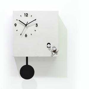 Puede incluir: Un reloj de cuco cuadrado blanco con manecillas y marcadores de hora negros. Una pequeña ilustración de un pájaro está en la parte inferior derecha. El reloj tiene un péndulo negro y el texto "Time Box" es visible.