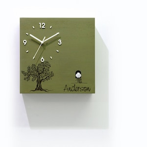 May include: A green wooden cuckoo clock with a white face and black hands. The clock features a black silhouette of a tree with the text "The Anderson" below it.