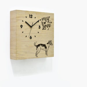 Puede incluir: Un reloj cuadrado de madera con agujas negras y una silueta de perro negra. La esfera del reloj tiene números negros y el texto "my love" con corazones y una flecha. El reloj está montado en una pared blanca.