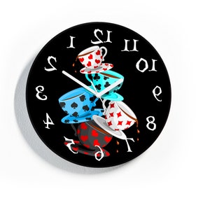 May include: A black clock with white numbers and a stack of four teacups with different colored designs. The teacups are stacked on top of each other and the top teacup is pouring tea. The clock is a whimsical design with a black background and white numbers.
