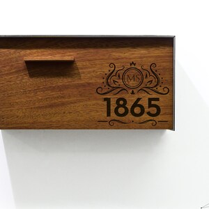 May include: A wooden plaque with a metal frame, featuring an engraved design with the initials "MS" and the year "1865".