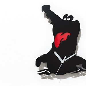 May include: Black silhouette of an alligator with a red tongue sticking out, with clock hands on the front. The alligator is in a swimming position with water ripples below it. The clock is on a white background.