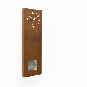 May include: A wooden wall clock with a pendulum. The clock face has white numbers and hands. The clock is brown with a light wood grain.