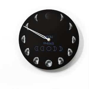 May include: A black circular clock with white moon phases around the edge. The clock hands are white and gold. The text "MOON PHASES" is printed in blue on the clock face.